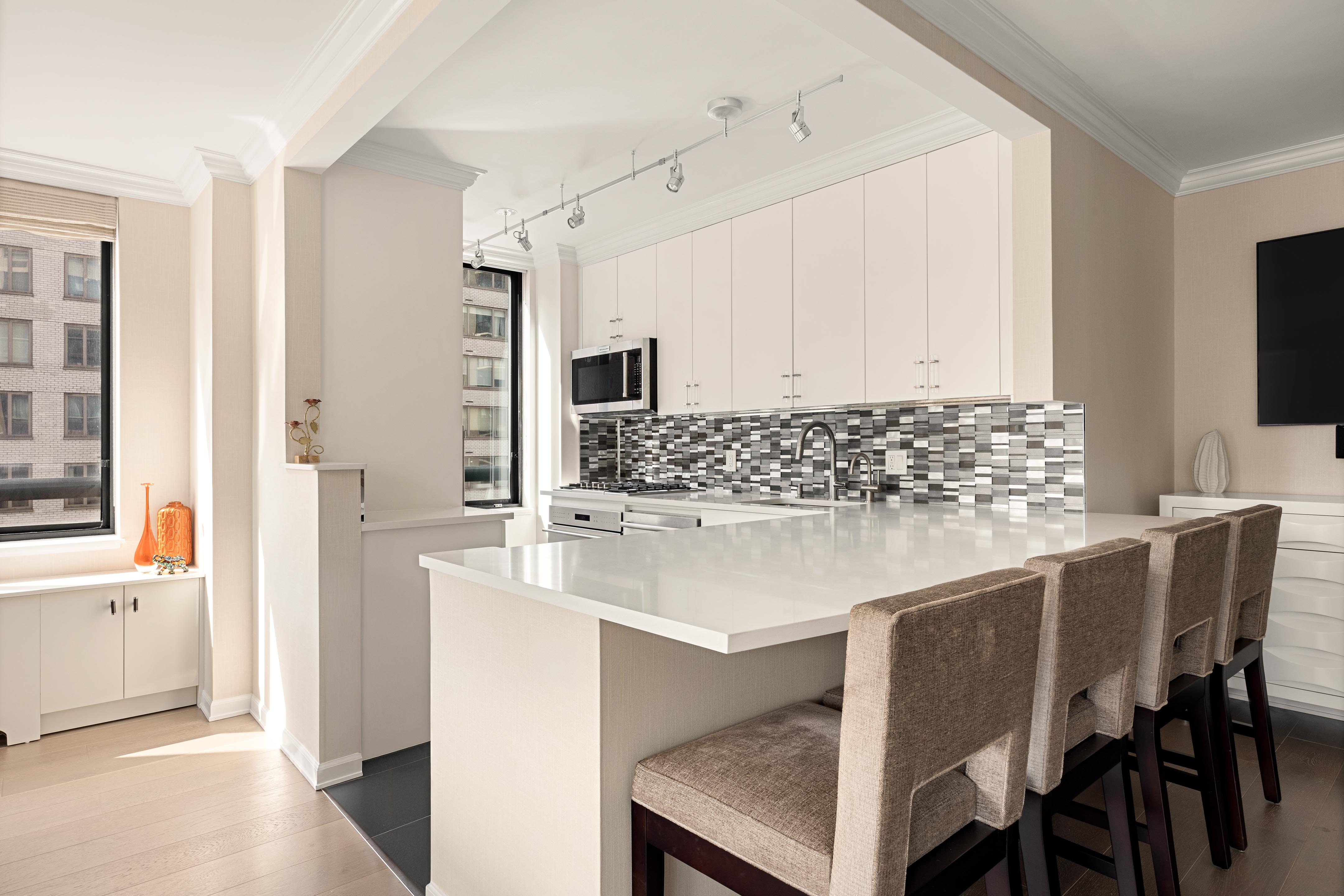 171 East 84th Street, Unit 7B Manhattan, NY 10028 - Photo 4 of 19 a kitchen with stainless steel appliances kitchen island granite countertop a table and chairs