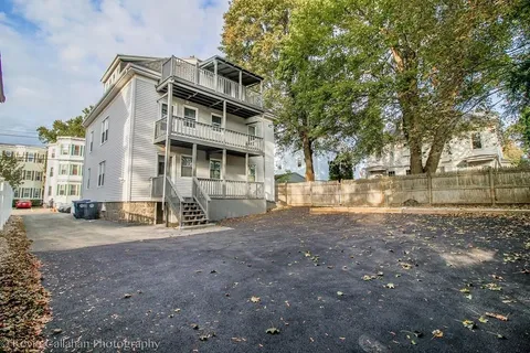 a view of a house with a yard and large trees