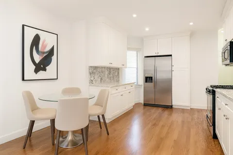 a kitchen with stainless steel appliances wooden floor and dining table