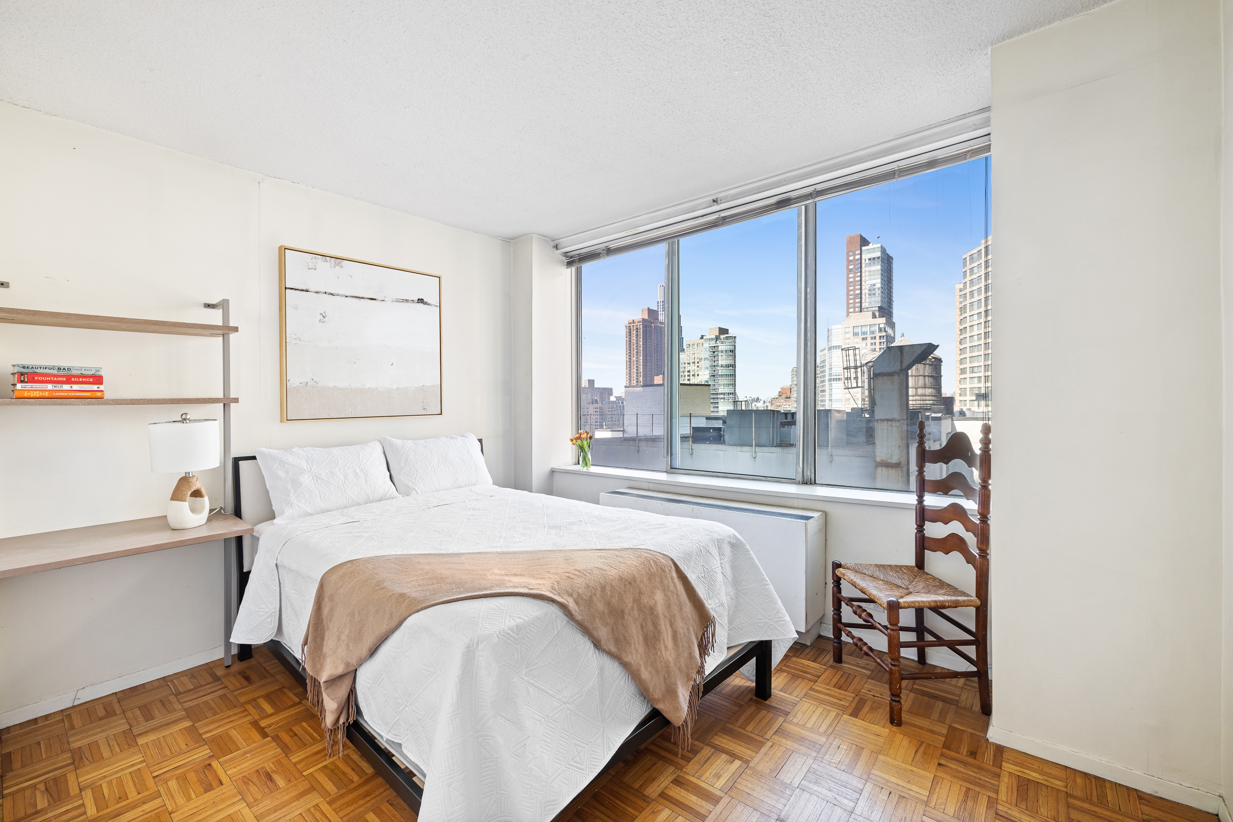 61 West 62nd Street, Unit 19C Manhattan, NY 10023 - Photo 2 of 7 a bedroom with a bed and a large window
