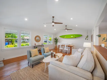 a living room with furniture kitchen view and a wooden floor