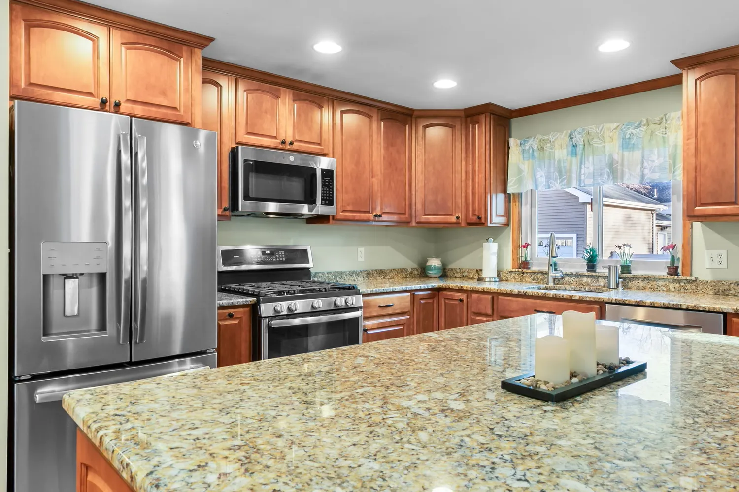 a kitchen with stainless steel appliances granite countertop a refrigerator a stove top oven a sink and dishwasher