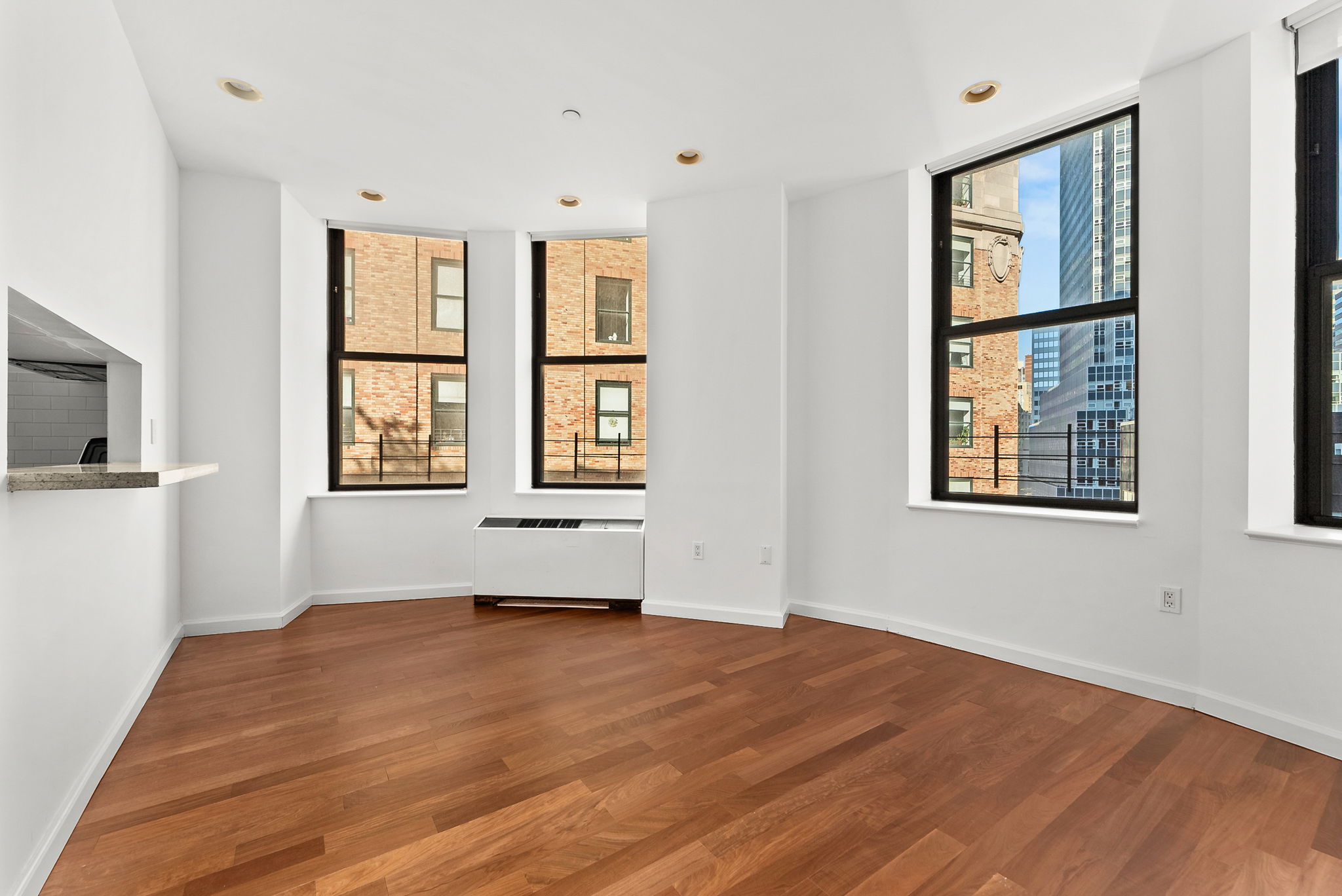 1 Wall Street Court, Unit 1405 Manhattan, NY 10005 - Photo 4 of 19 a view of an empty room with wooden floor and a window