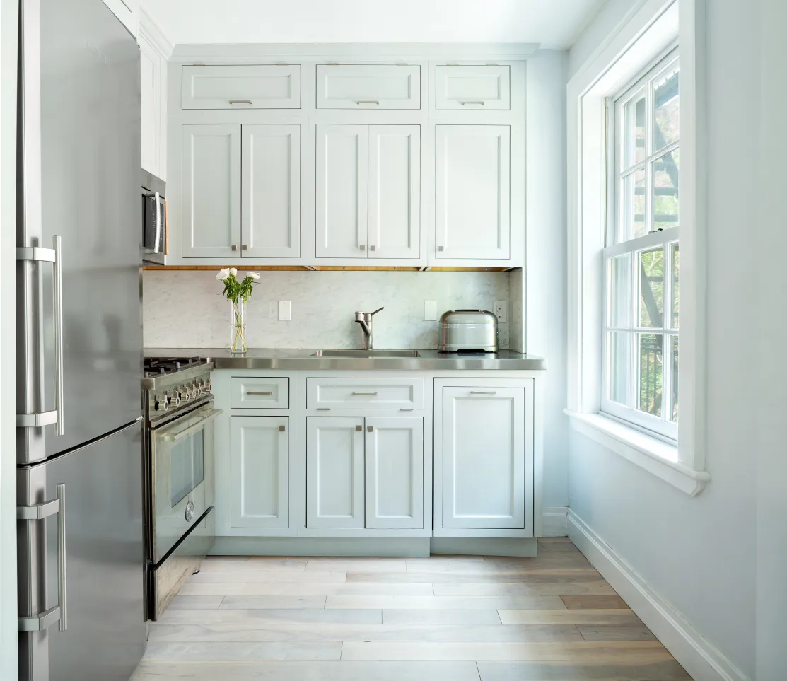 a kitchen with white cabinets and window