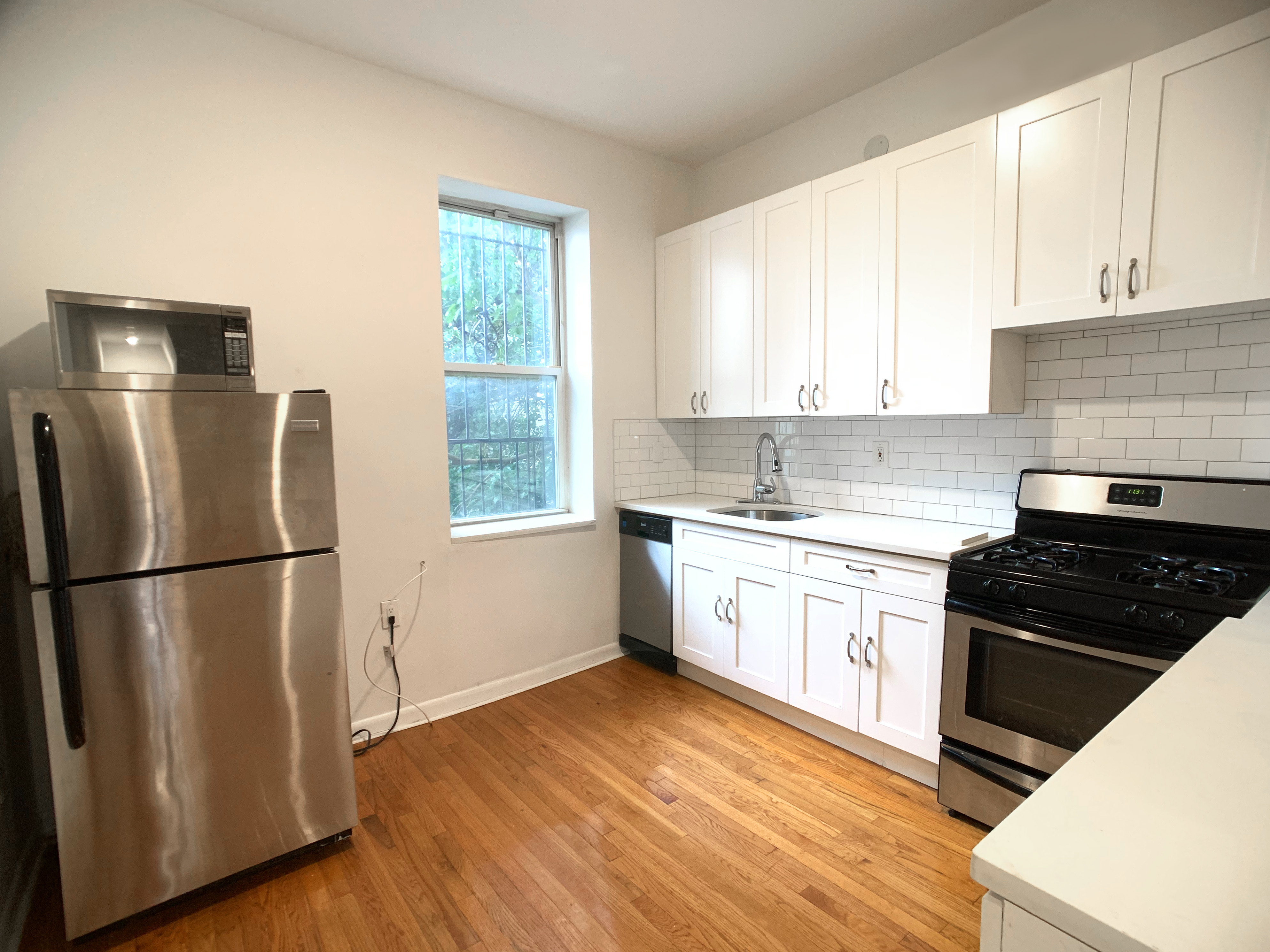 293 Tompkins Avenue, Unit 2 Brooklyn, NY 11221 - Photo 1 of 11 a kitchen with a refrigerator a stove a sink wooden floor and cabinets