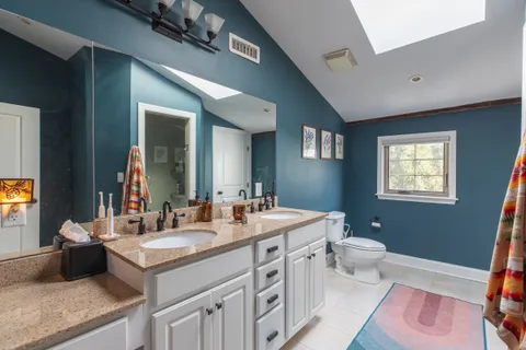 a bathroom with a double vanity sink a toilet and a mirror