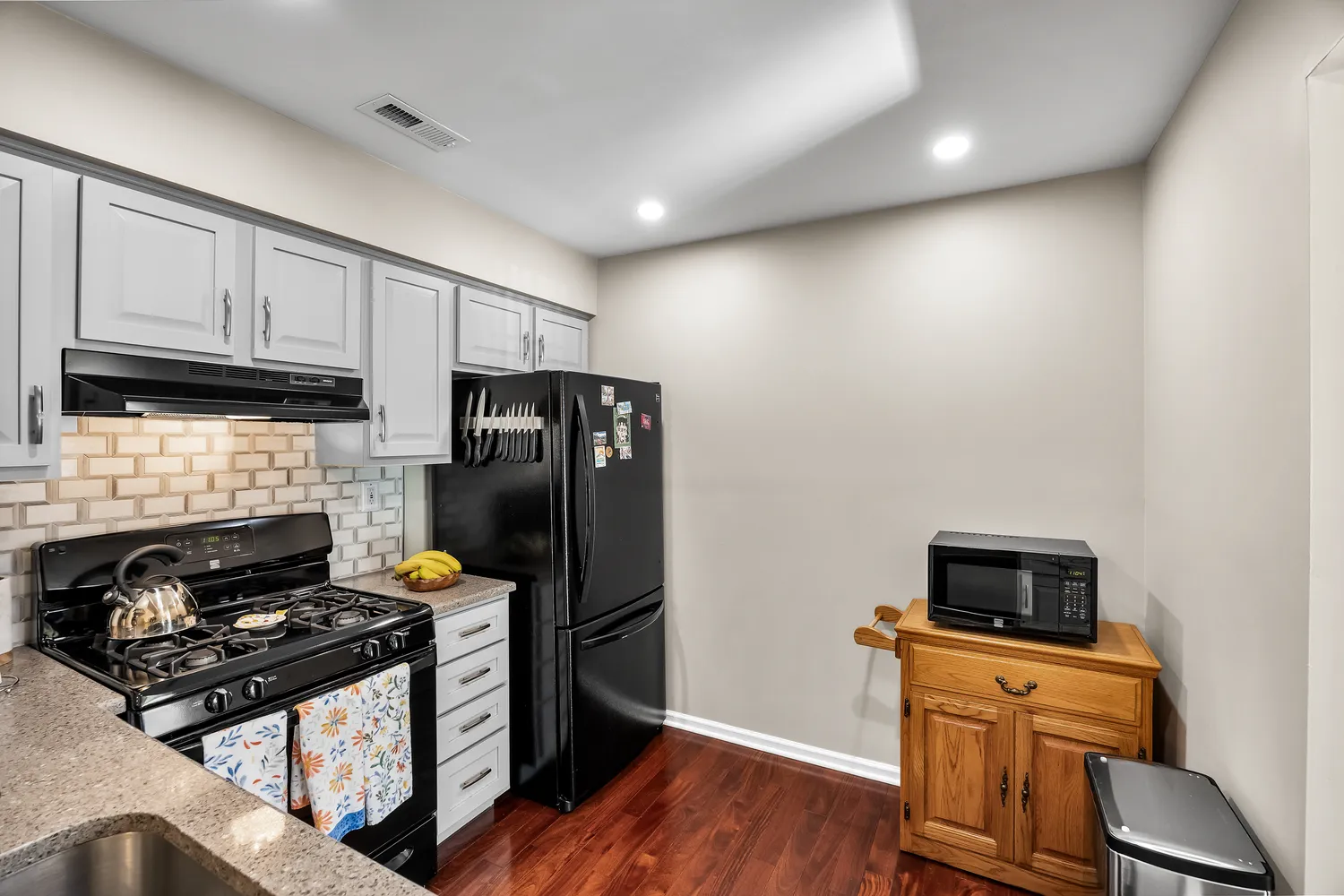 a kitchen with stainless steel appliances a stove a refrigerator a sink a stove wooden floor and cabinets