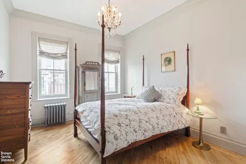 a bedroom with a bed chandelier and a window