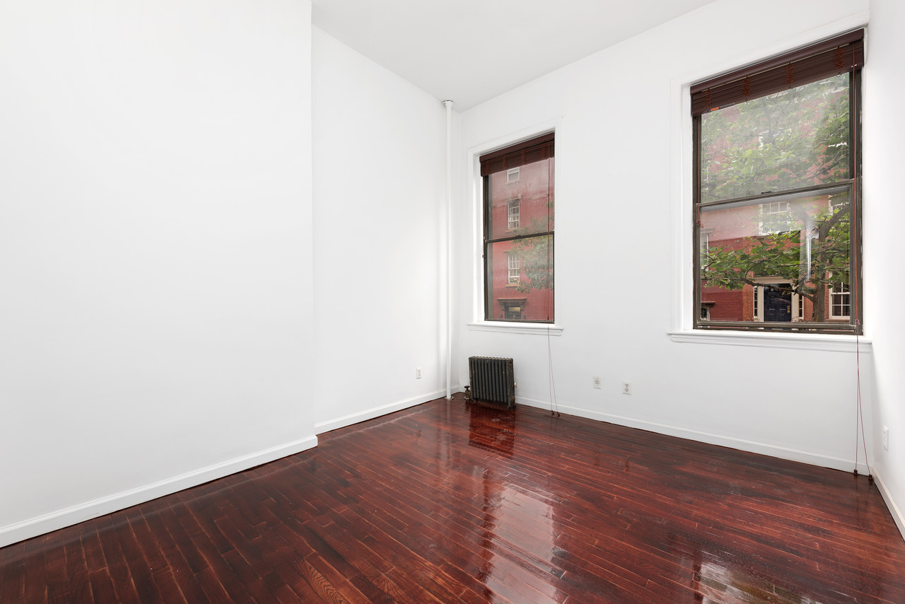 54 Jane Street Manhattan, NY 10014 - Photo 7 of 26 an empty room with wooden floor and windows