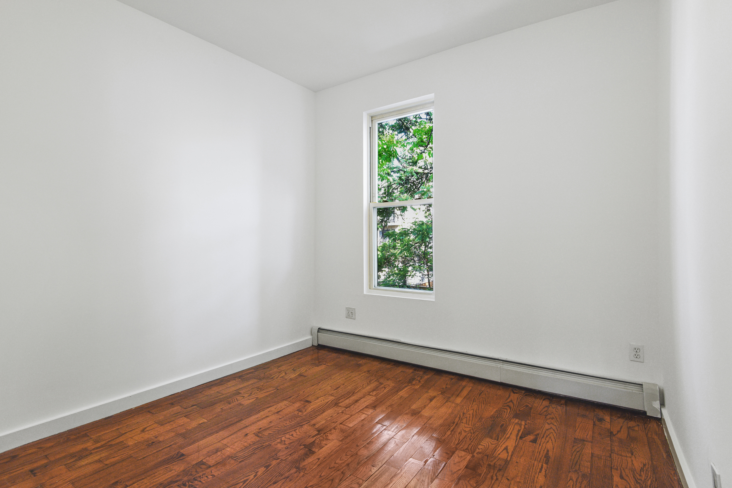 1076 Decatur Street, Unit 2 Brooklyn, NY 11207 - Photo 5 of 11 an empty room with wooden floor and window