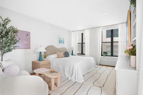 a spacious bedroom with two beds and large window with potted plants