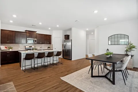 a kitchen with stainless steel appliances kitchen island granite countertop a table chairs microwave and sink