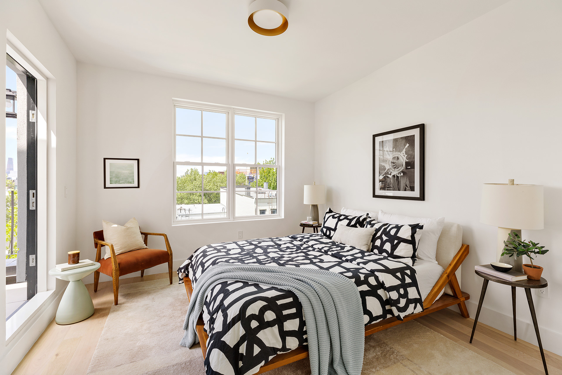 185 Ainslie Street, Unit 3 Brooklyn, NY 11211 - Photo 4 of 12 a bed sitting in a bedroom next to a window with a lamp and a large window