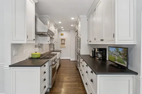 a kitchen with stainless steel appliances a stove top oven a sink a counter space and cabinets
