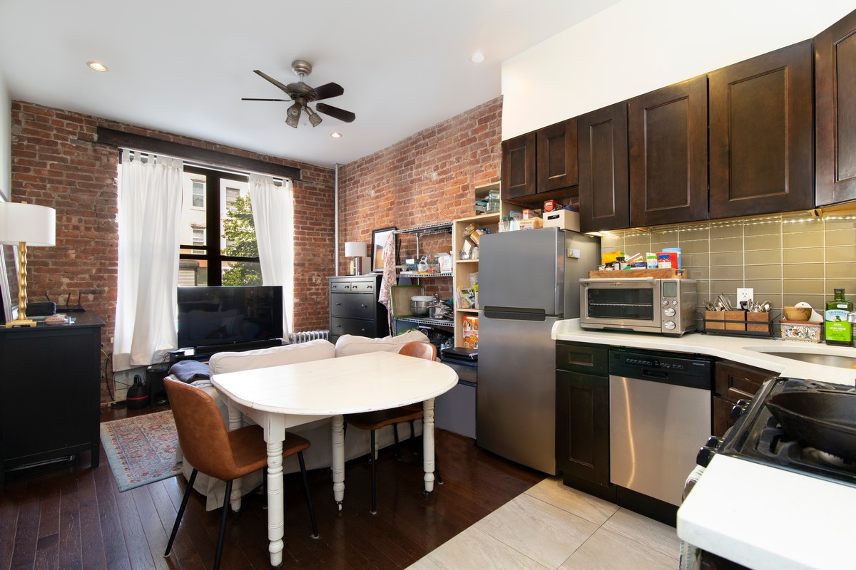 a kitchen with stainless steel appliances granite countertop a dining table chairs refrigerator and sink