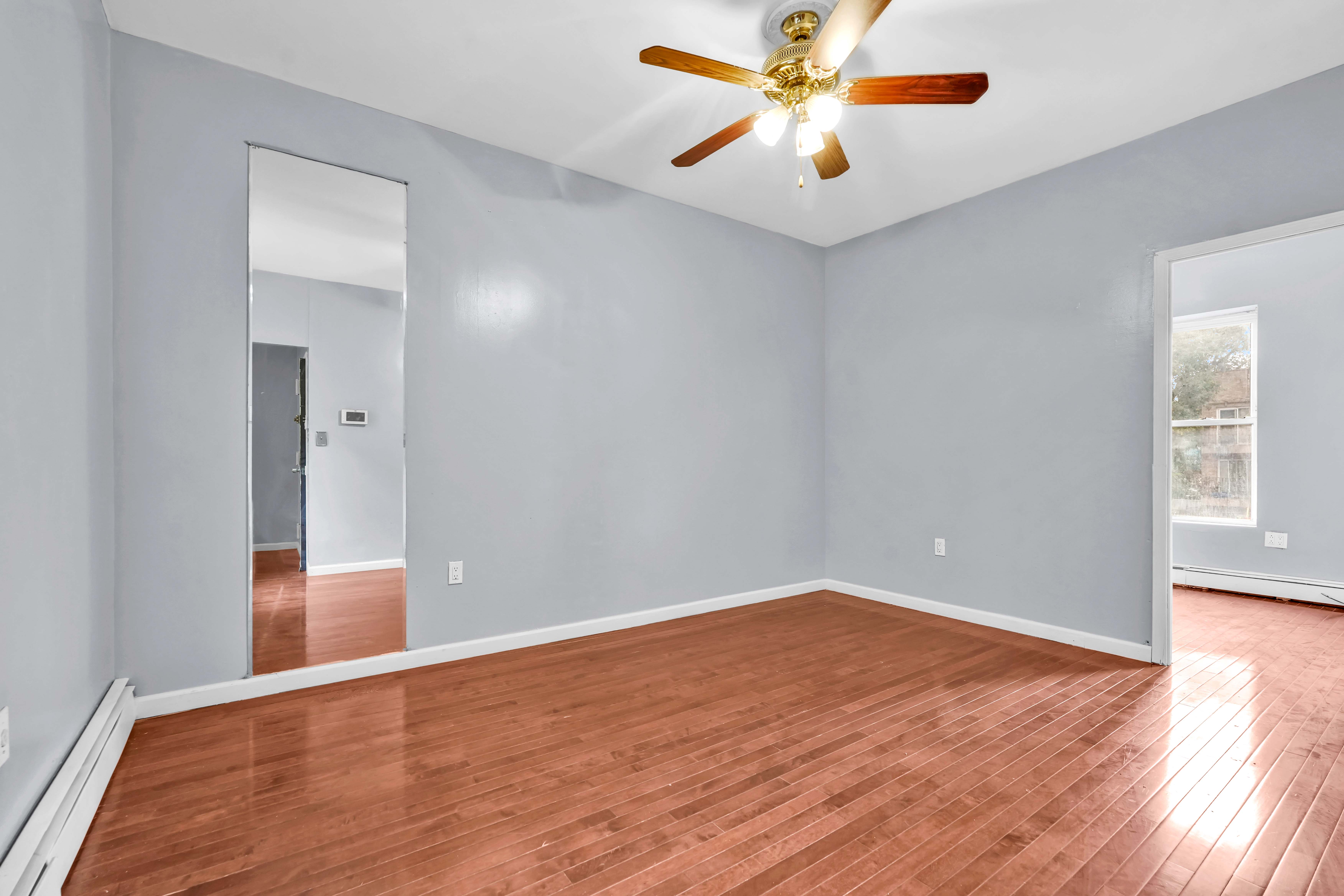 1633 St Johns Place, Unit 3 Brooklyn, NY 11233 - Photo 8 of 29 an empty room with wooden floor and windows