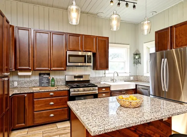 a kitchen with stainless steel appliances granite countertop wooden cabinets a stove top oven a sink and dishwasher