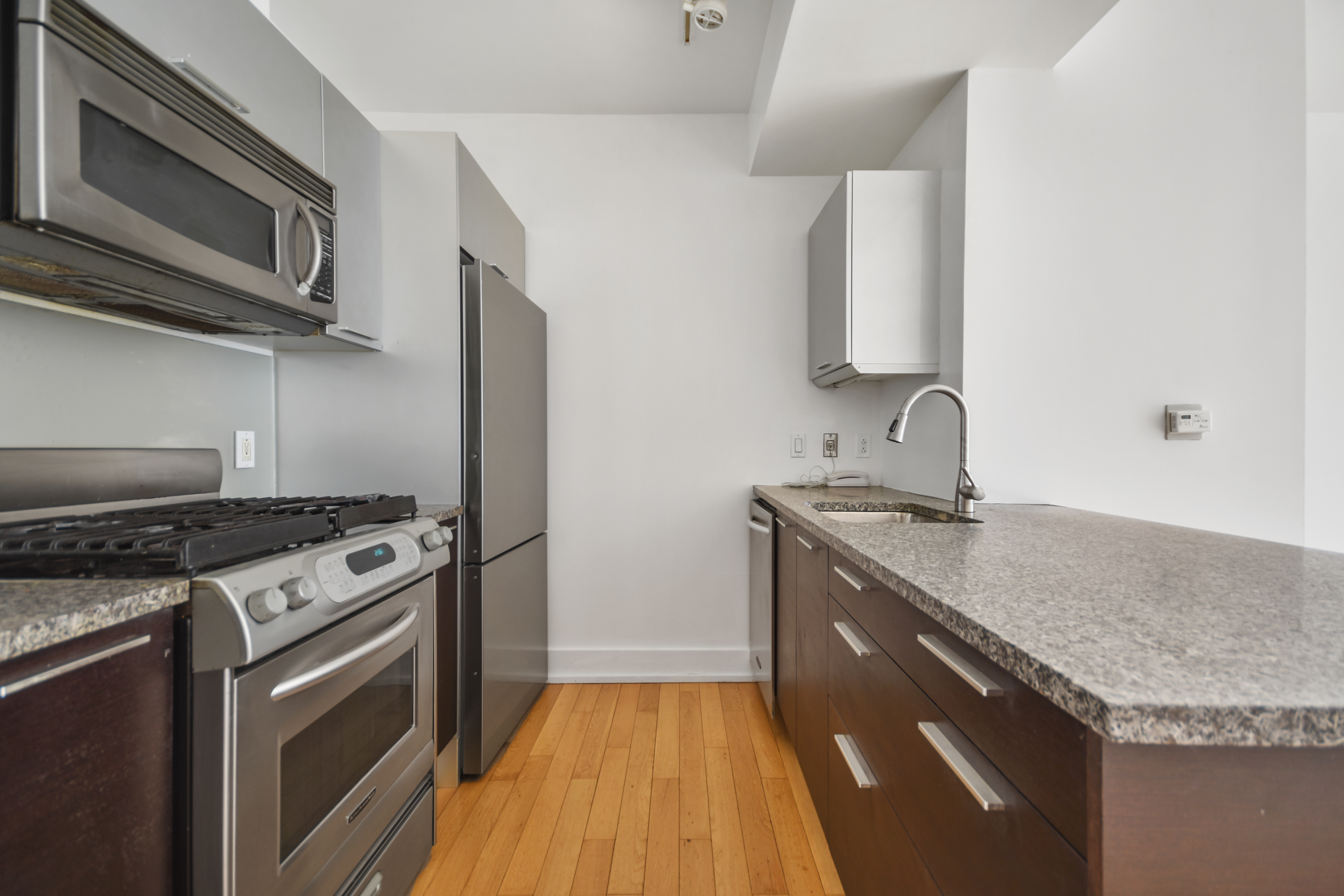 350 West 42nd Street, Unit 8H Manhattan, NY 10036 - Photo 4 of 11 a kitchen with stainless steel appliances granite countertop a sink stove and microwave