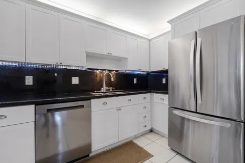 a kitchen with granite countertop white cabinets and stainless steel appliances