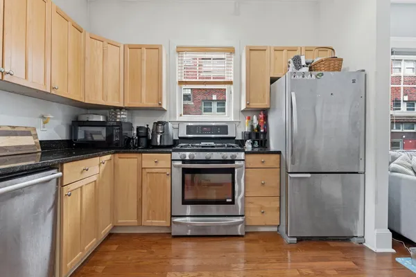 a kitchen with granite countertop a refrigerator stove and cabinets