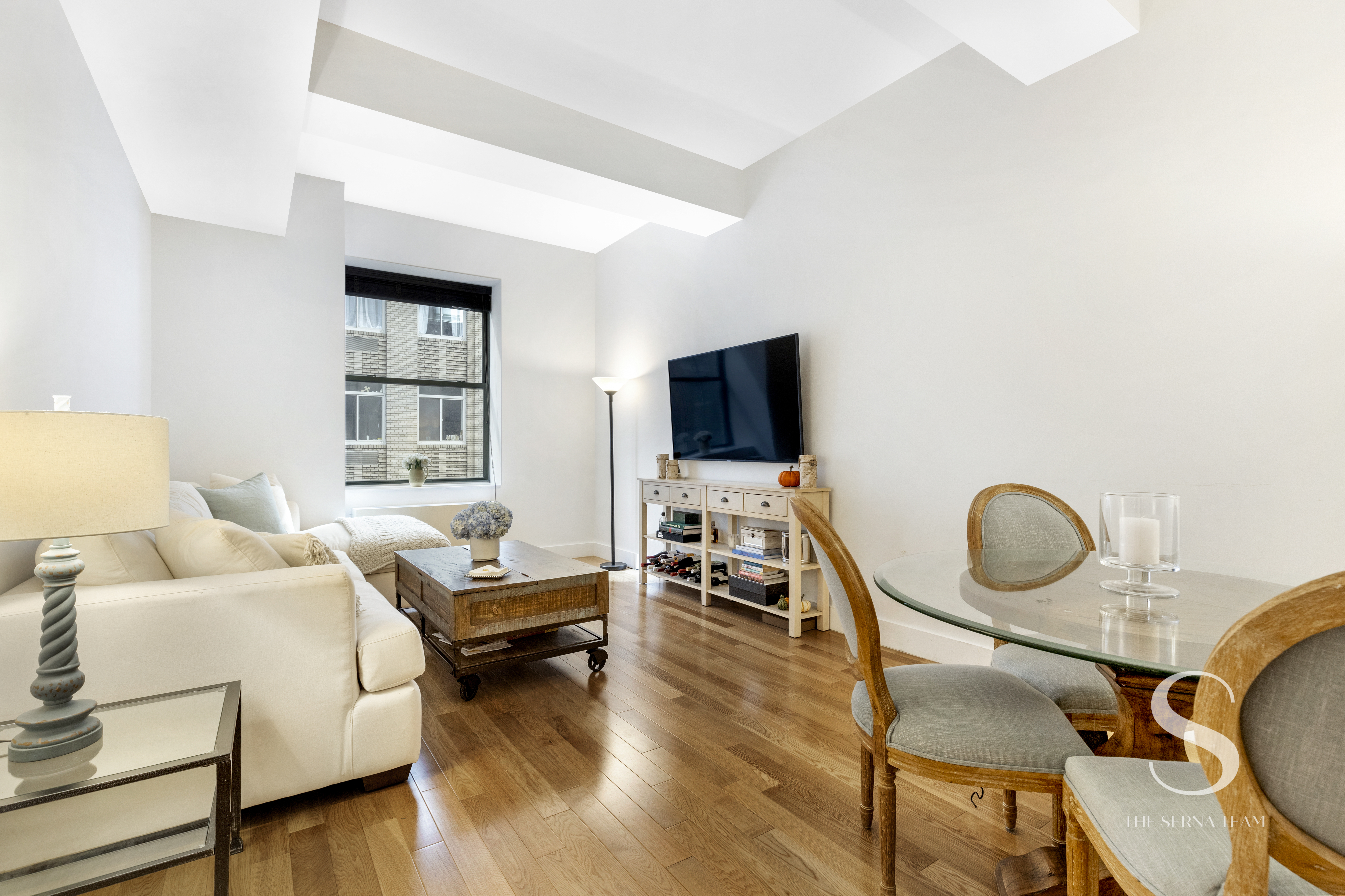 99 John Street, Unit 910 Manhattan, NY 10038 - Photo 3 of 11 a living room with furniture and a flat screen tv