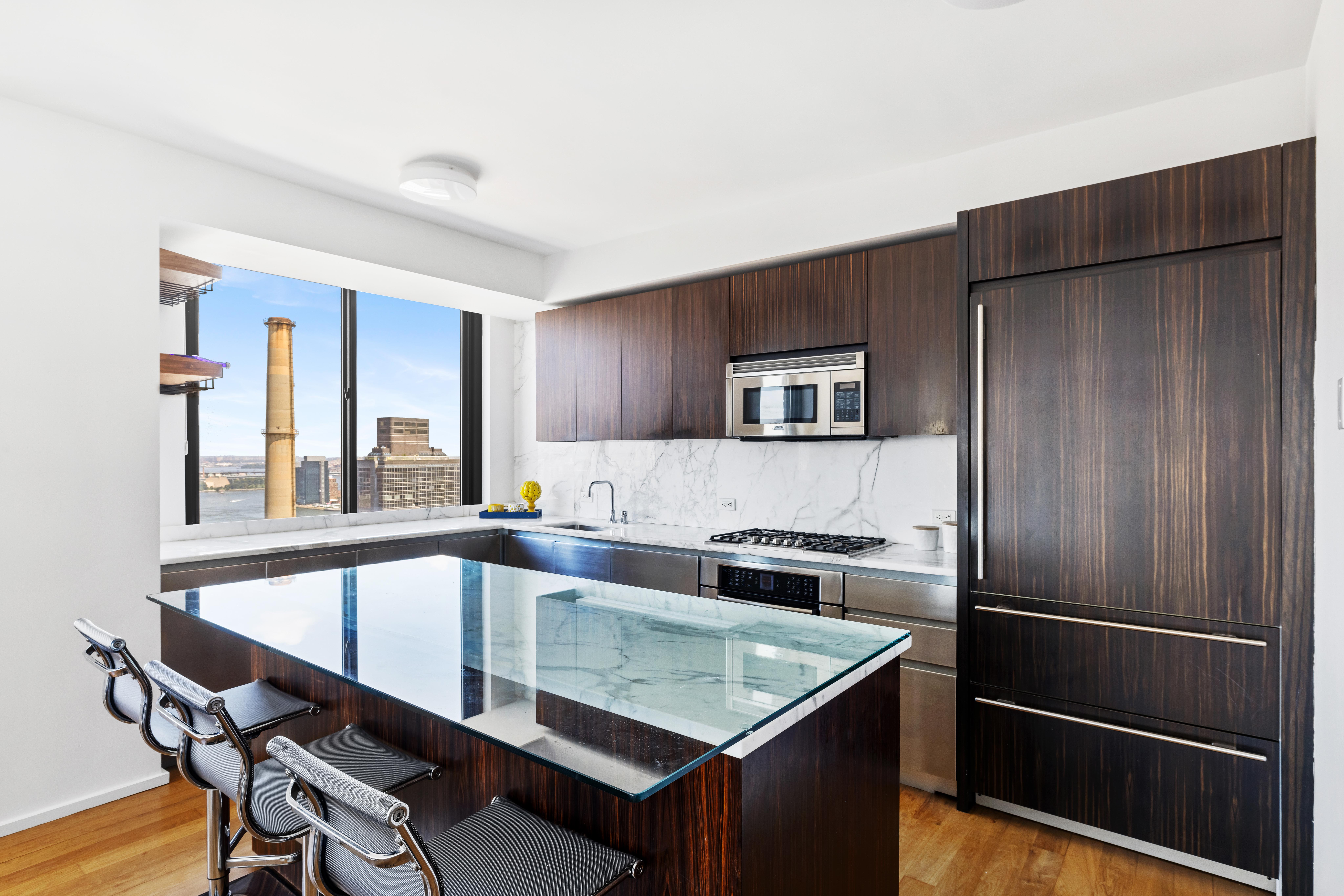515 East 72nd Street, Unit 40E Manhattan, NY 10021 - Photo 7 of 34 a kitchen with a table chairs refrigerator and microwave