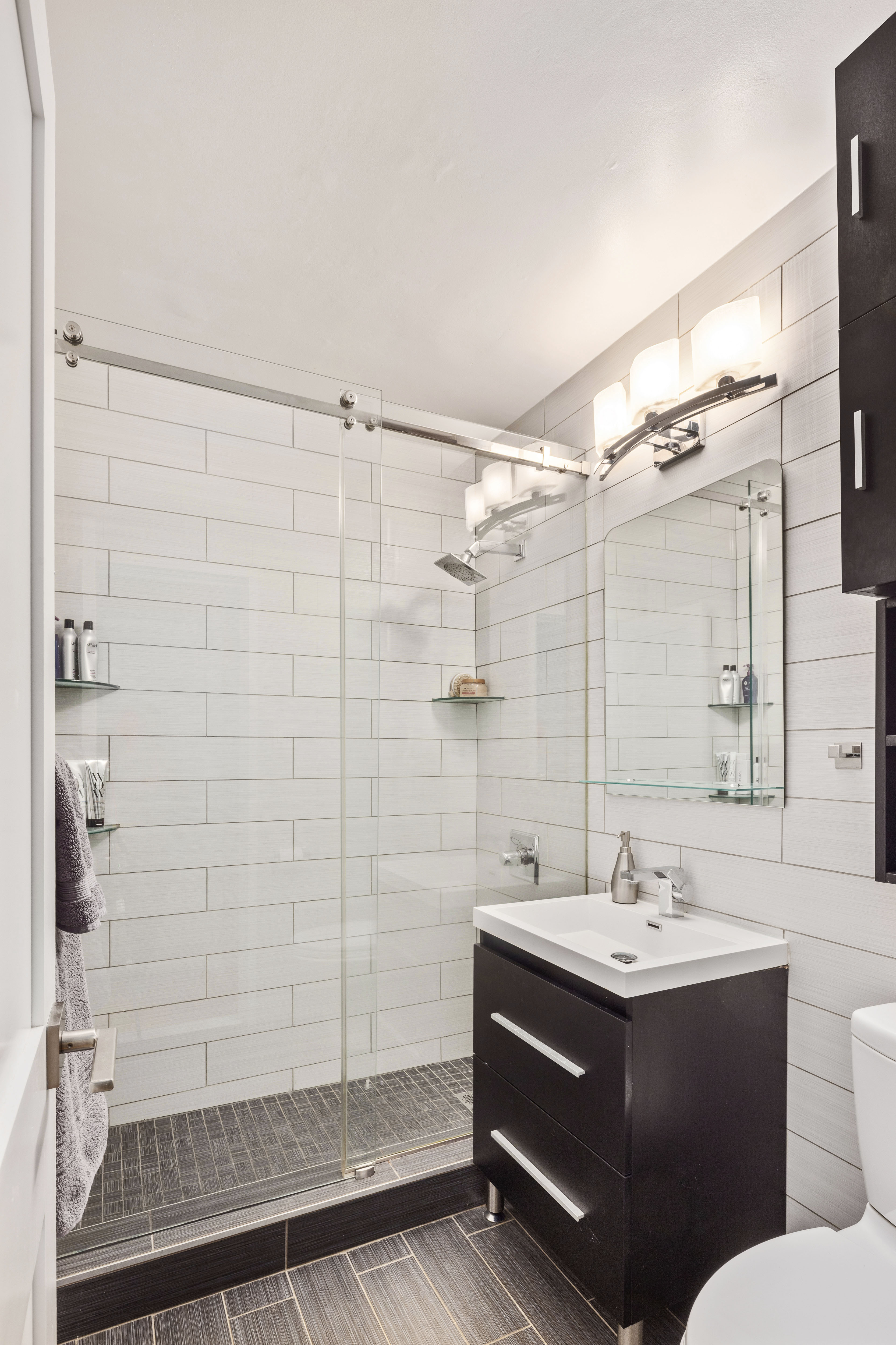 159 West 53rd Street, Unit 34E Manhattan, NY 10019 - Photo 9 of 15 a bathroom with a sink mirror toilet and shower