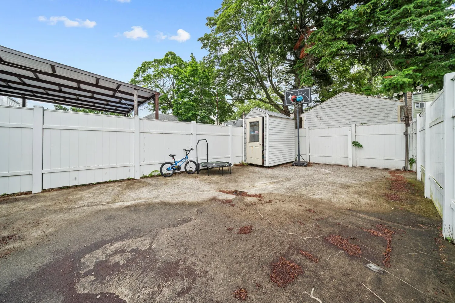 a view of white house with a large tree and wooden fence