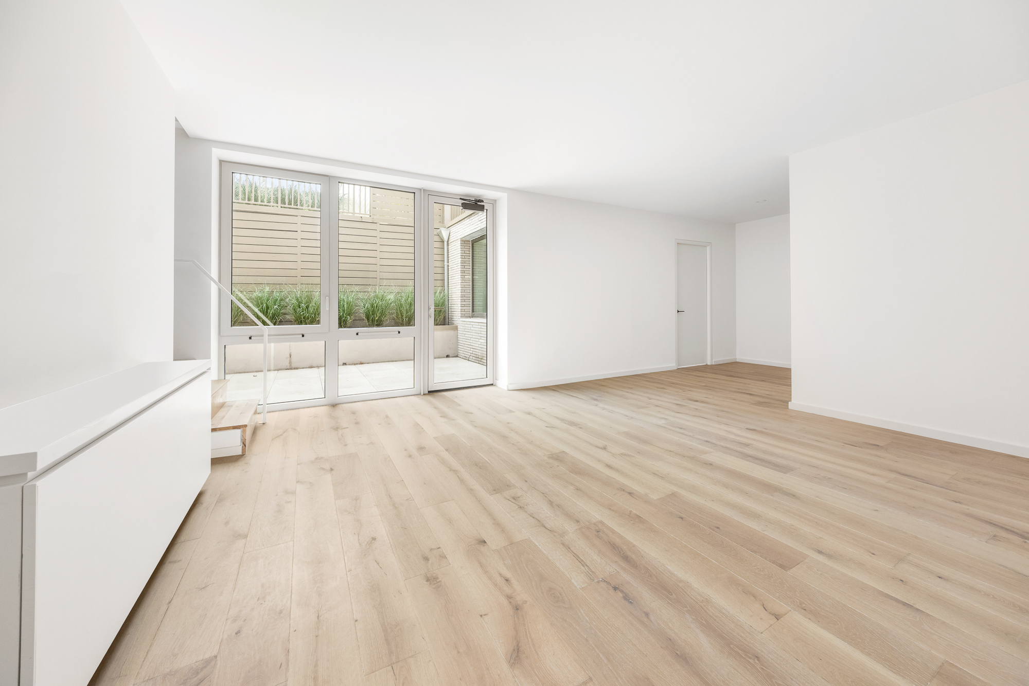 66 Clinton Street, Unit 1A Manhattan, NY 10002 - Photo 9 of 20 a view of an empty room with wooden floor and a window