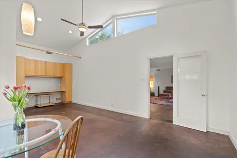 a view of a livingroom and a dining room with a chandelier fan