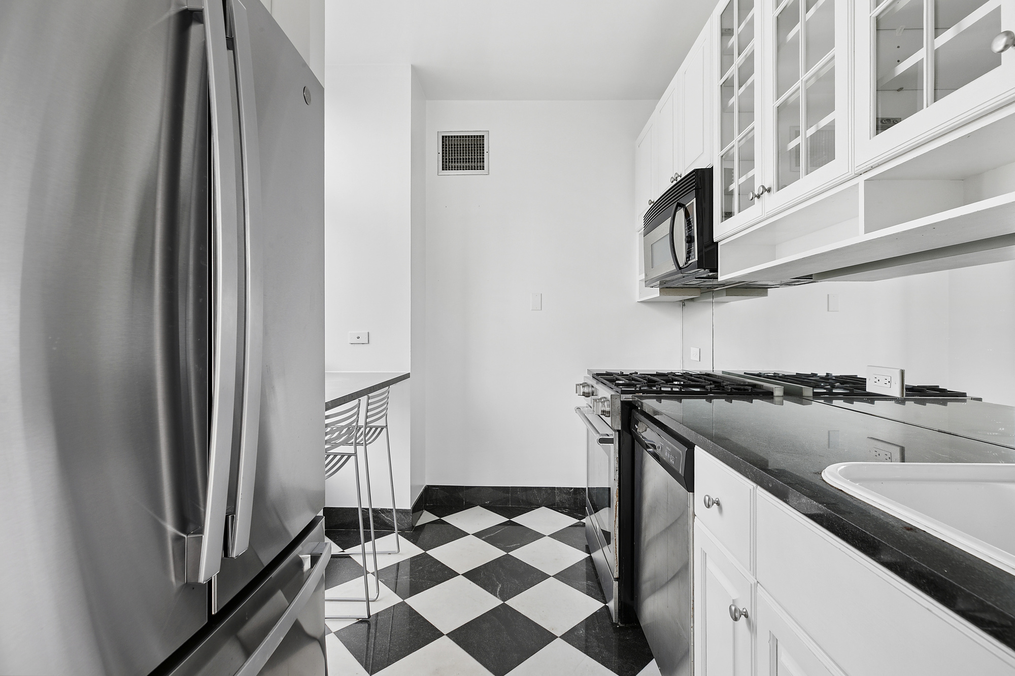 250 East 54th Street, Unit 35A Manhattan, NY 10022 - Photo 7 of 13 a kitchen with a stove a sink and a refrigerator