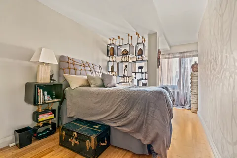 a bed sitting in a bedroom next to a window with tv and pillows