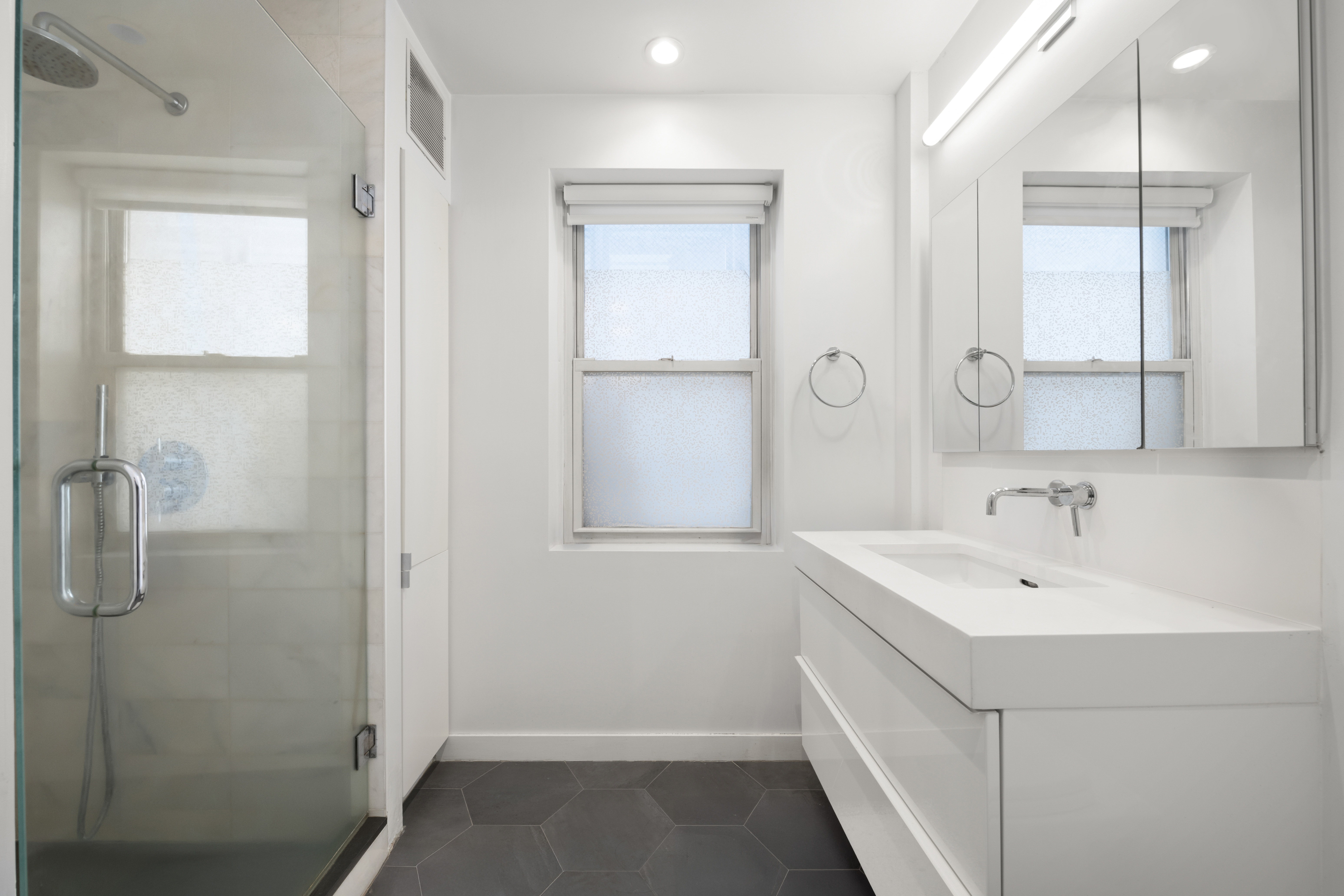 221 East 50th Street, Unit 6D/7D Manhattan, NY 10022 - Photo 12 of 19 a bathroom with a sink a mirror and shower