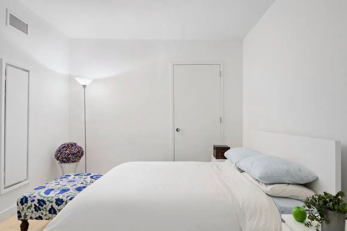 a bedroom with a bed and a potted plant