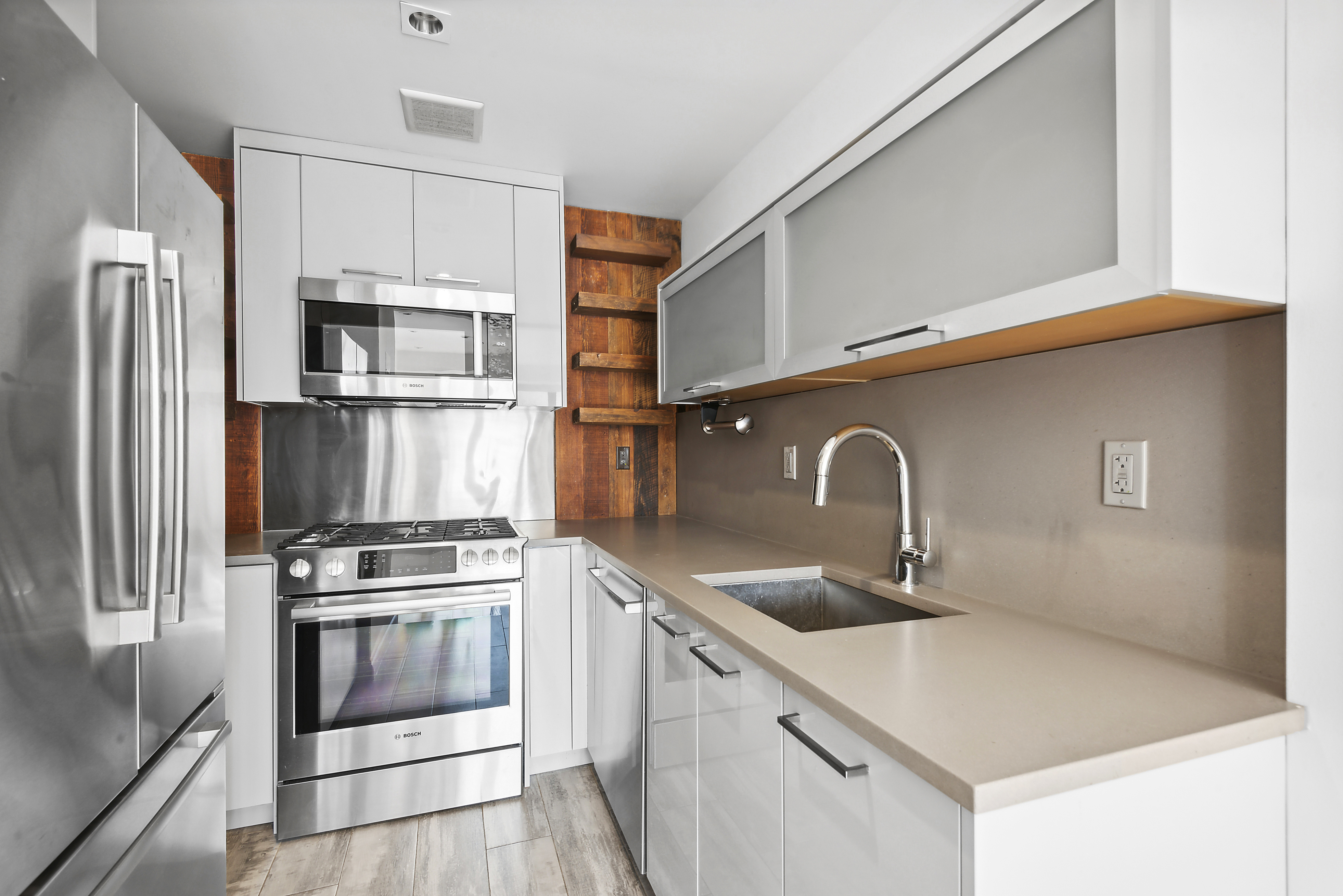 27 Dodworth Street, Unit PHF Brooklyn, NY 11221 - Photo 11 of 18 a kitchen with stainless steel appliances a sink a stove and a refrigerator with wooden floor