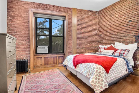 a bed sitting in front of a brick house with a large windows