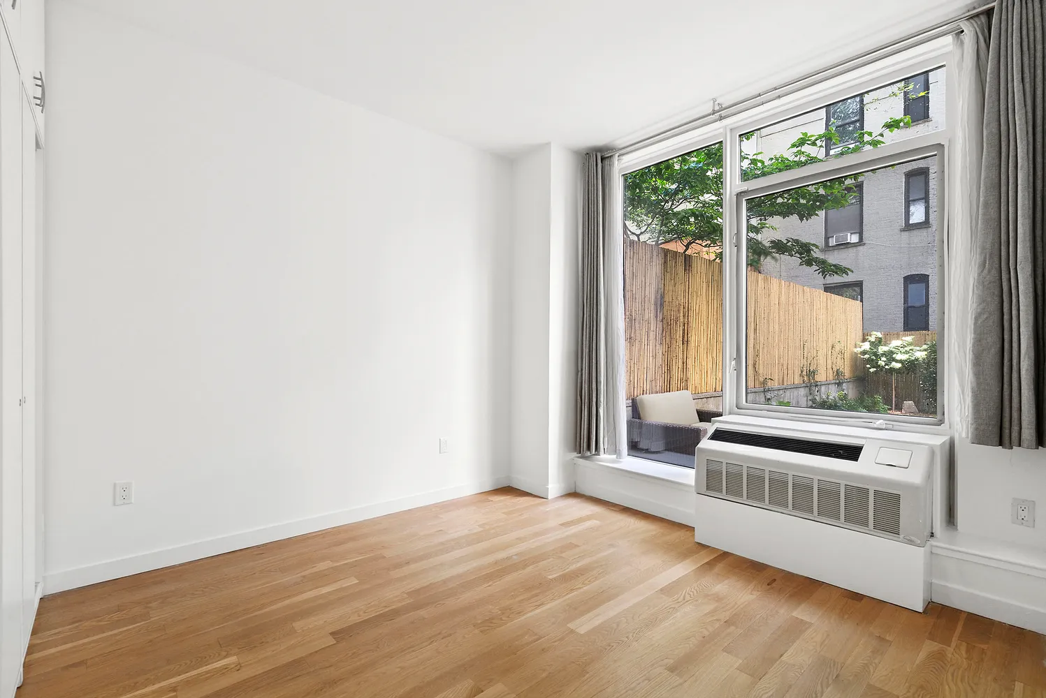 an empty room with wooden floor and windows