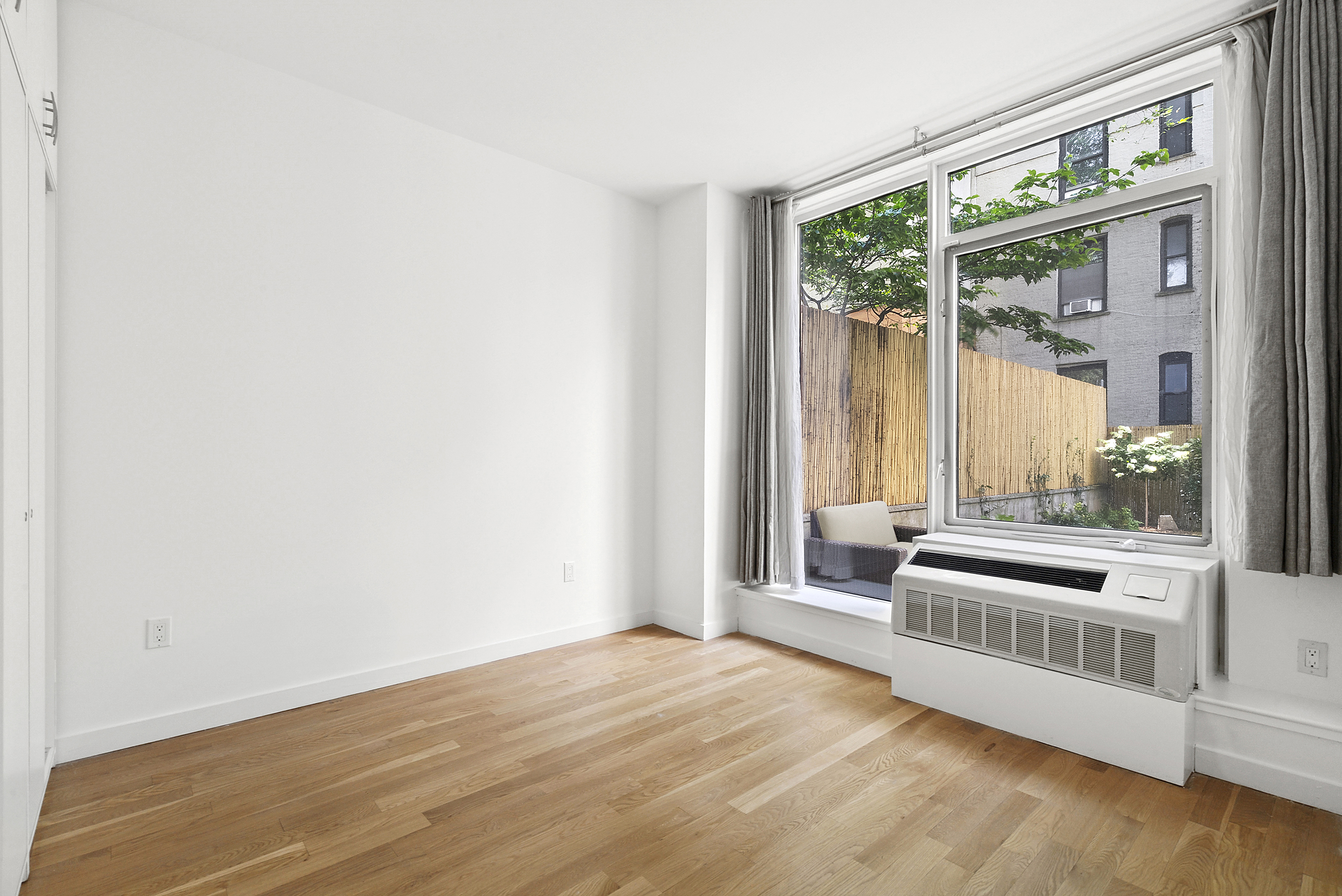 306 West 116th Street, Unit 1B Manhattan, NY 10026 - Photo 9 of 14 an empty room with wooden floor and windows
