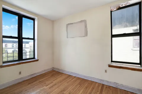 a view of empty room with window and wooden floor