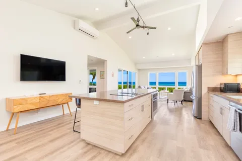 a large white kitchen with a flat screen tv and a couch