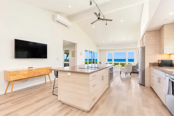 a large white kitchen with a flat screen tv and a couch