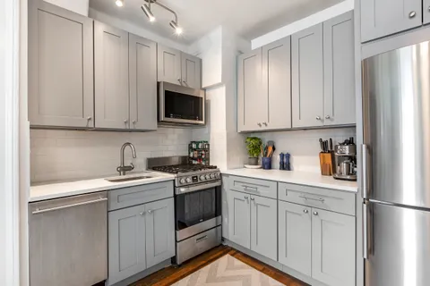 a kitchen with stainless steel appliances granite countertop white cabinets sink and a refrigerator