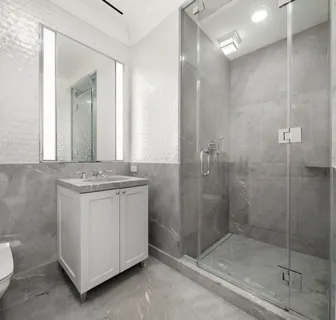 a bathroom with a granite countertop sink a mirror and shower