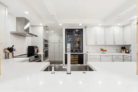 a kitchen with kitchen island a counter top space a sink stainless steel appliances and cabinets