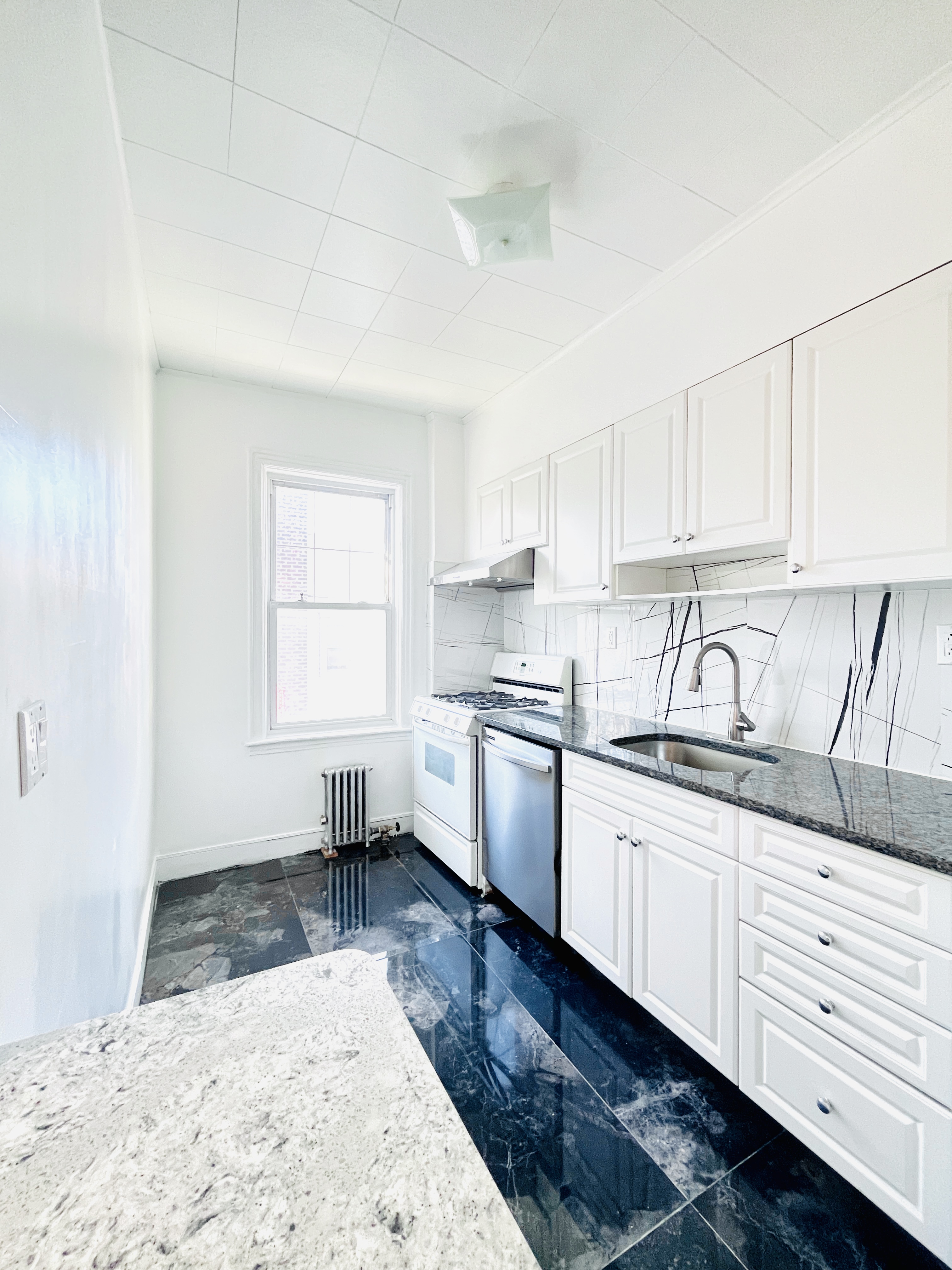 63-33 Haring Street, Unit 2F Queens, NY 11374 - Photo 3 of 7 a kitchen with granite countertop white cabinets white appliances a sink and dishwasher