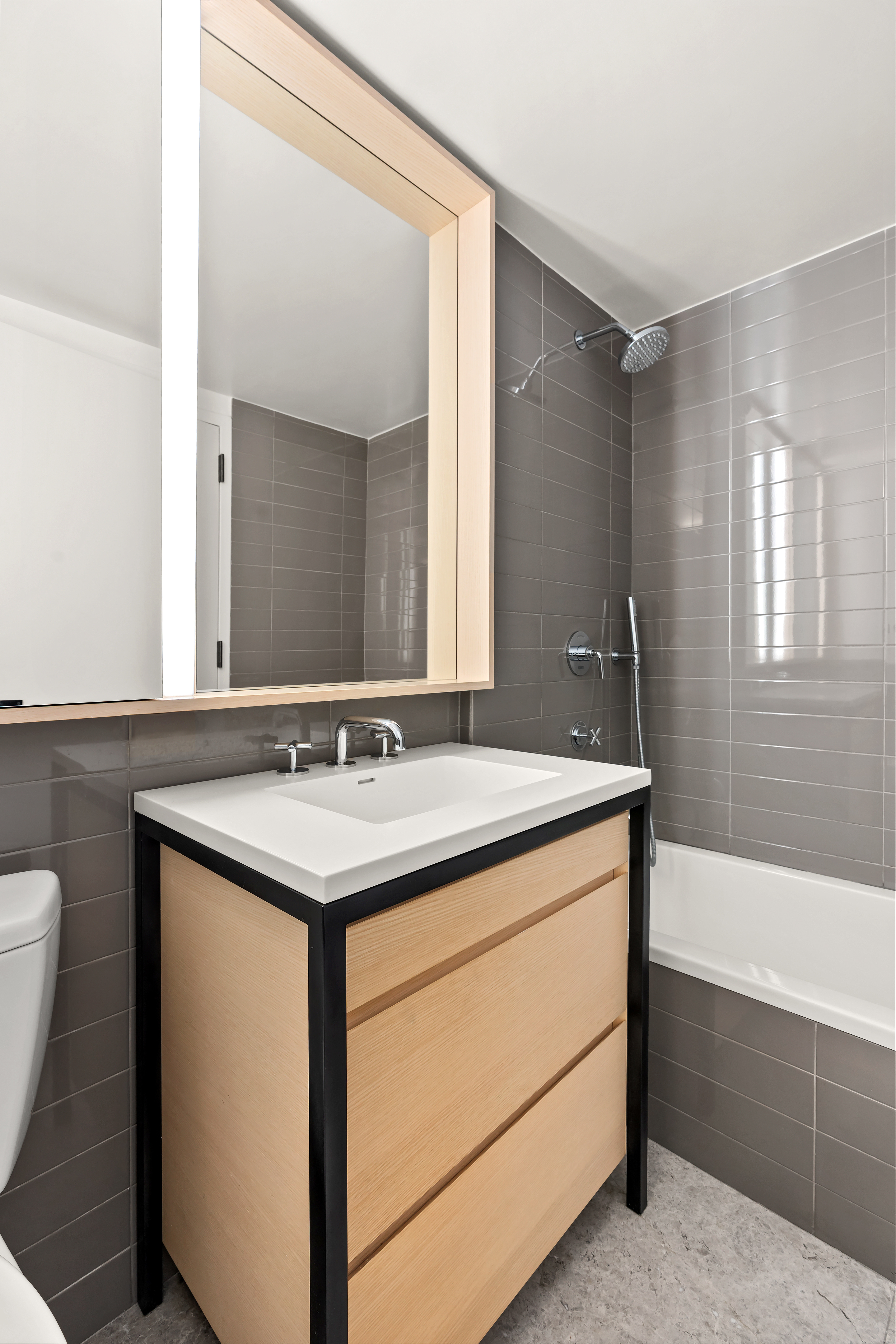 385 1st Avenue, Unit 20B Manhattan, NY 10010 - Photo 8 of 10 a bathroom with a granite countertop sink a toilet a mirror and bathtub