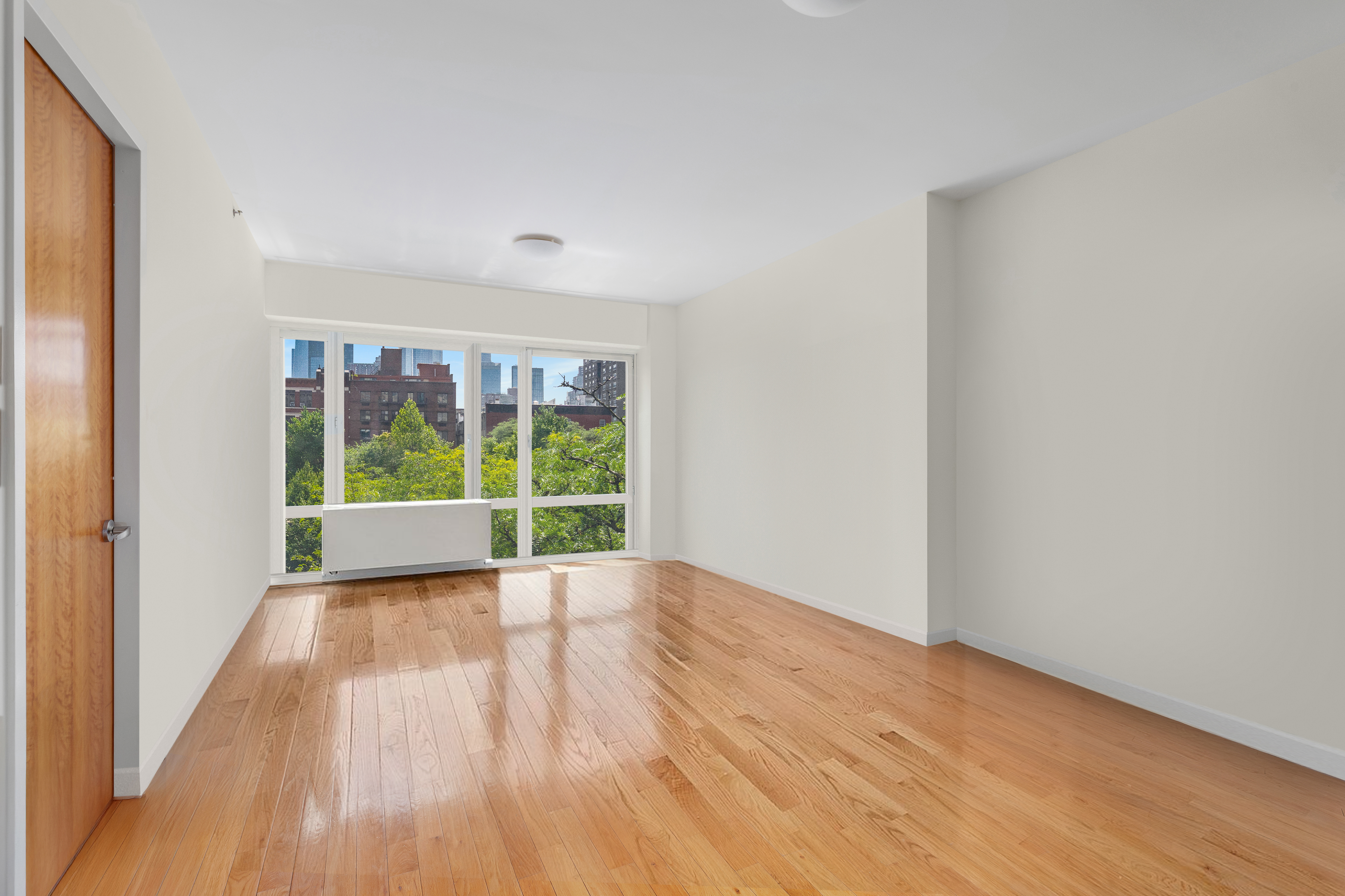 454 West 54th Street, Unit 3P Manhattan, NY 10019 - Photo 2 of 9 a view of an empty room with wooden floor and a window
