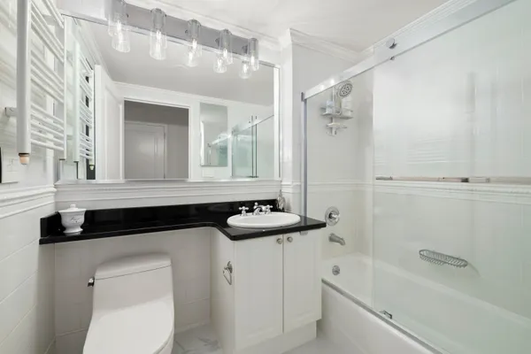 a bathroom with a granite countertop sink a toilet a mirror and bathtub