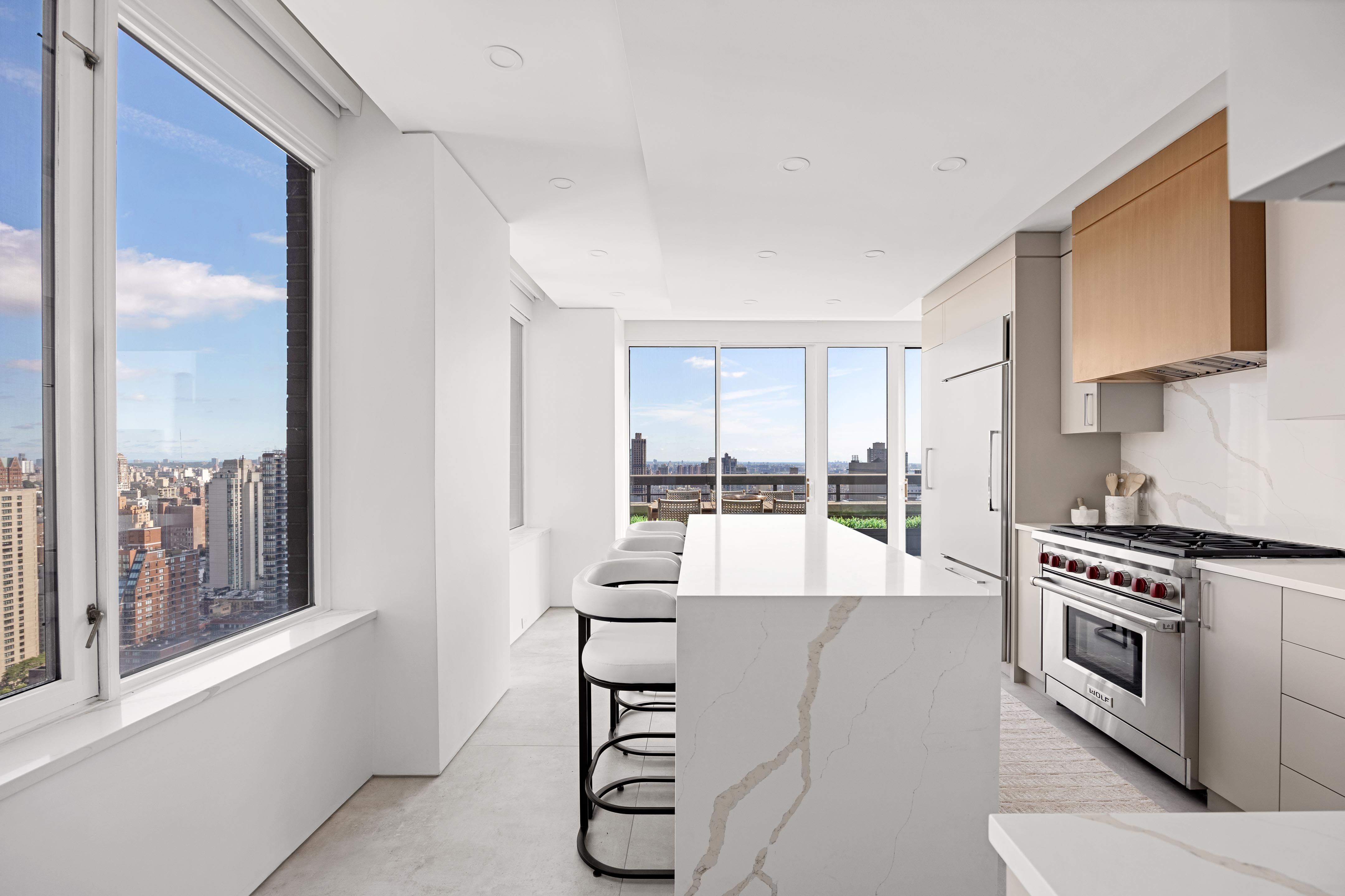 422 East 72nd Street, Unit 37AD Manhattan, NY 10021 - Photo 11 of 38 a large kitchen with stainless steel appliances a stove and a large window