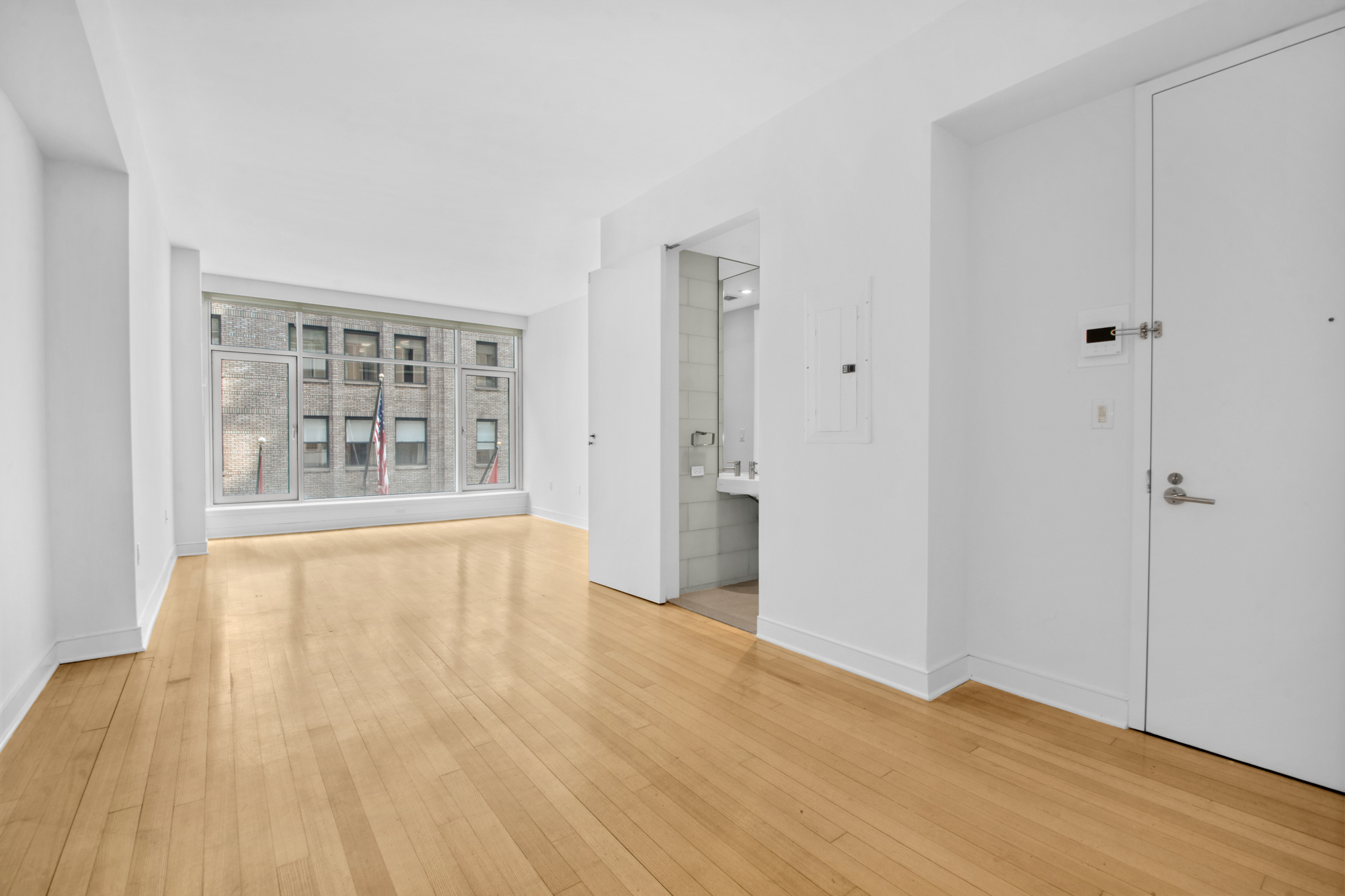 5 East 44th Street, Unit 5A Manhattan, NY 10017 - Photo 1 of 15 a view of an empty room with wooden floor and a window